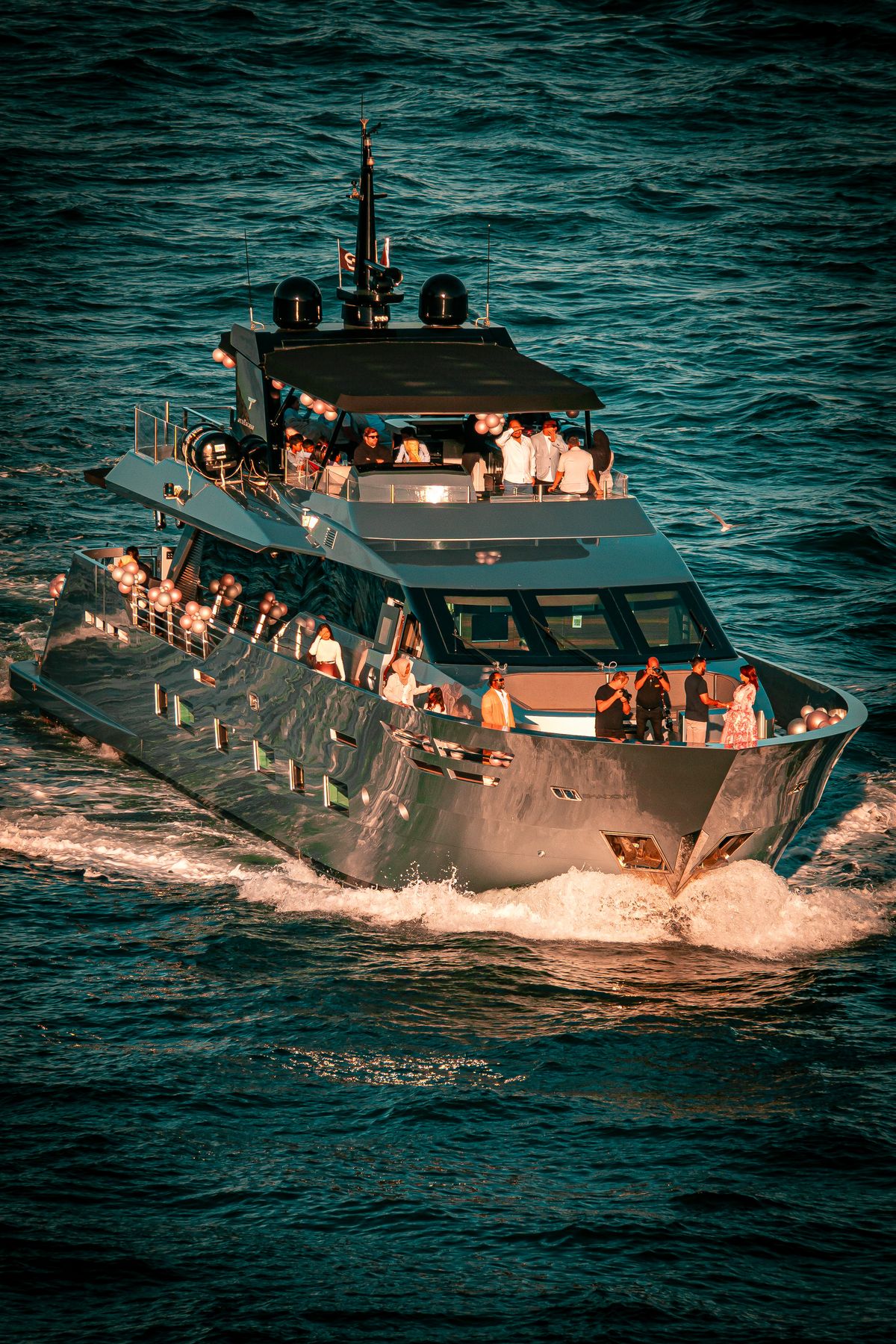 Luxury charter yacht with guests on deck cruising Sydney Harbour, seen from above