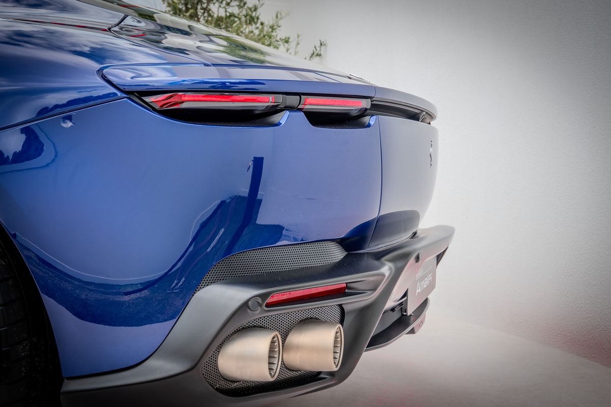 Rear quarter of a blue Ferrari Amalfi showing its tail lights and twin titanium exhausts
