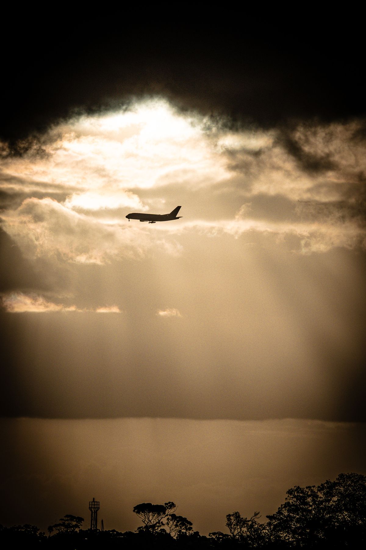 Silhouette of a jet under storm clouds and breaking sun rays