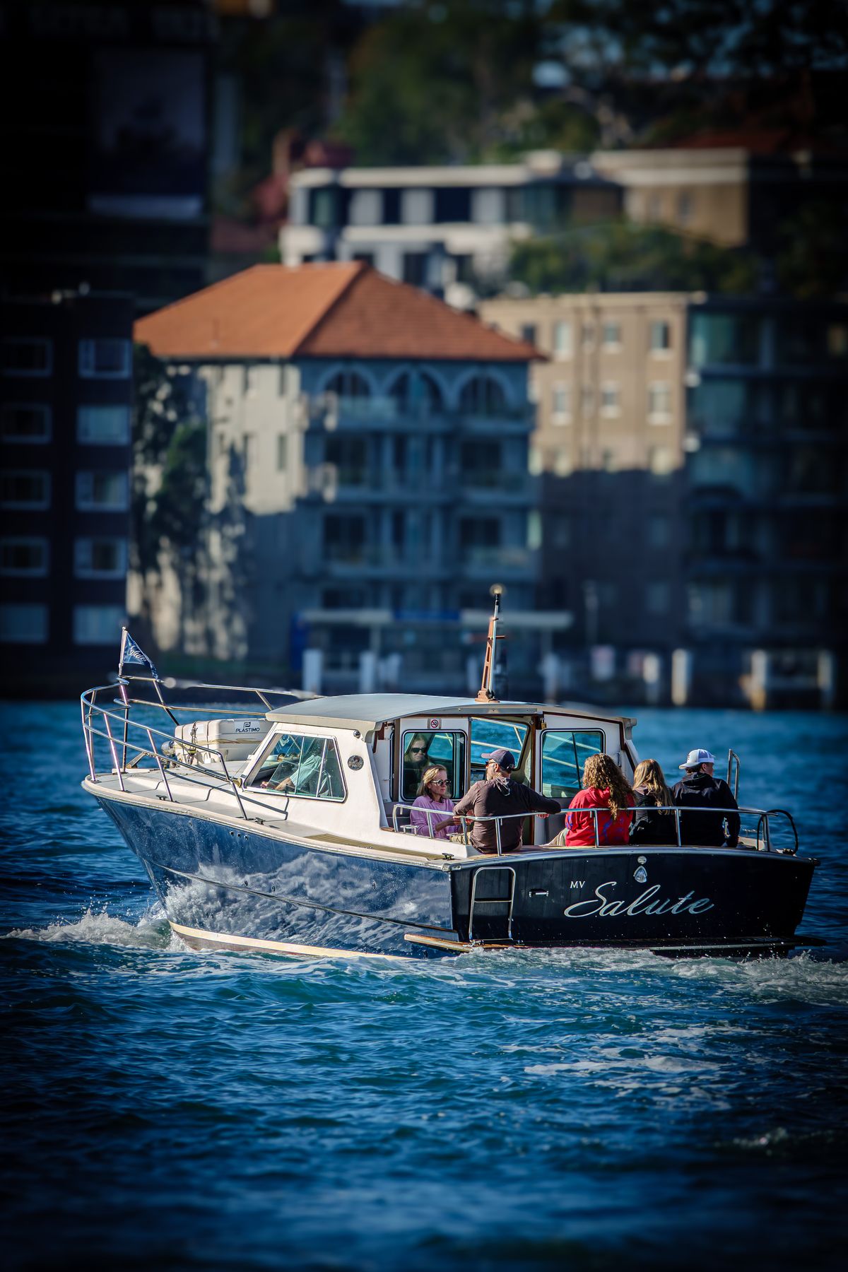 Motor launch MV Salute cruising past harbourside homes on Sydney Harbour