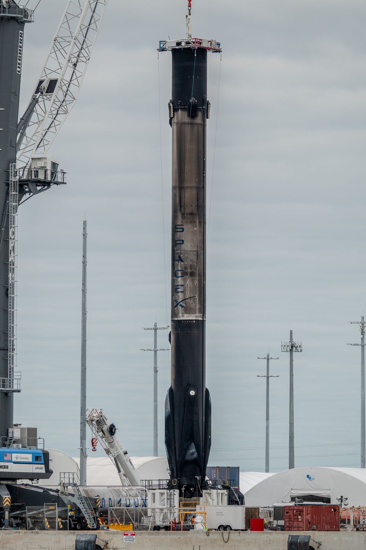 Recovered, soot-covered SpaceX Falcon 9 booster standing upright at Port Canaveral
